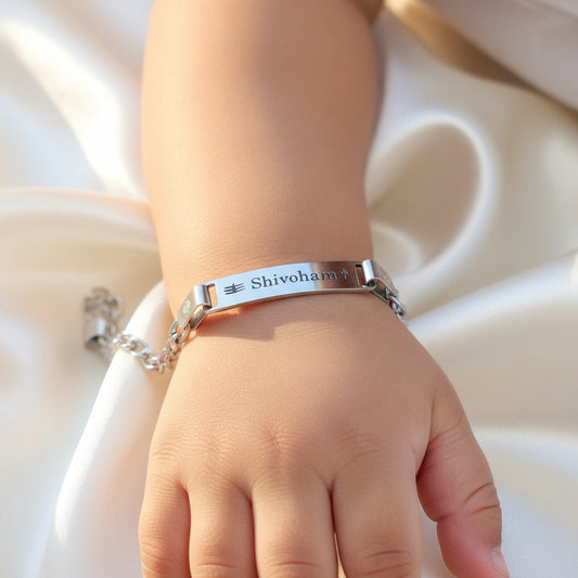 Silver bracelet with 'Shivoham' engraved on a toddlers wrist against a neutral background