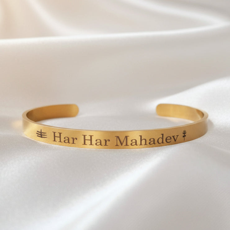 Gold bracelet with 'Har Har Mahadev' engraving on a white fabric background