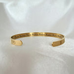 Gold bracelet with engraved text on a white background