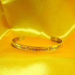 Golden finish Lord Ganesha bracelet with engraved text on a yellow satin background
