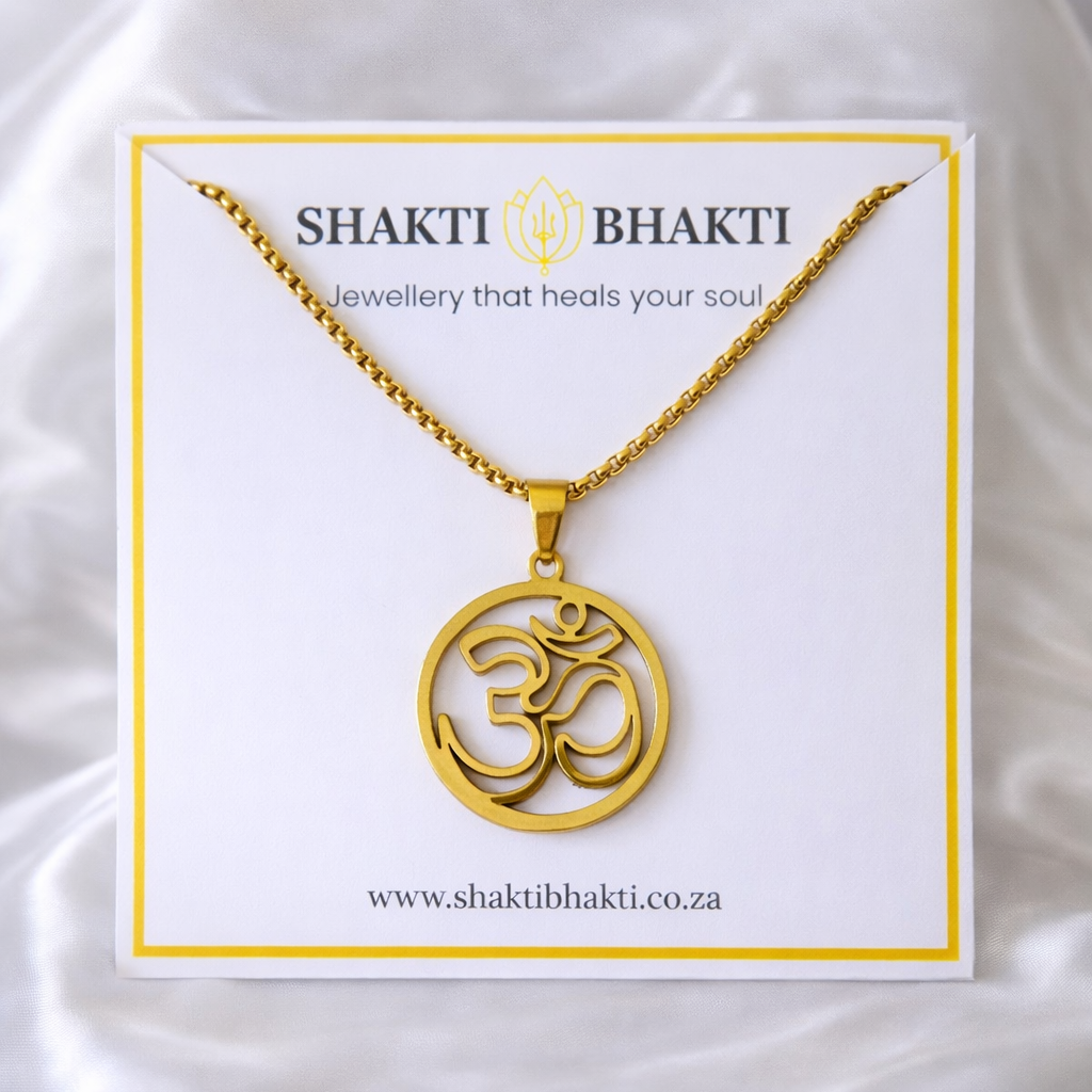 Gold necklace with Om symbol on a Shakti Bhakti branded card against a white background