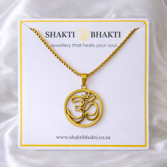 Gold necklace with Om symbol on a Shakti Bhakti branded card against a white background