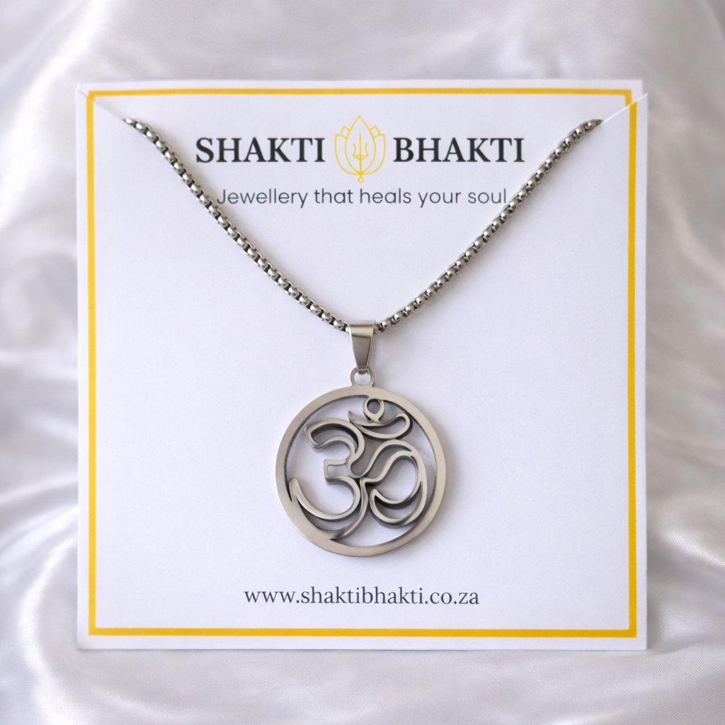 Silver necklace with Om symbol on a Shakti Bhakti branded card against a white satin background